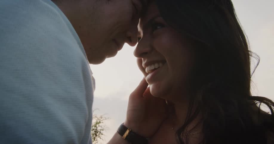 A man holds a womans head as he leans against her forhead