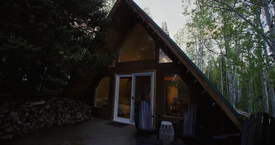 Lights turns on inside a small cabin on the woods at evening