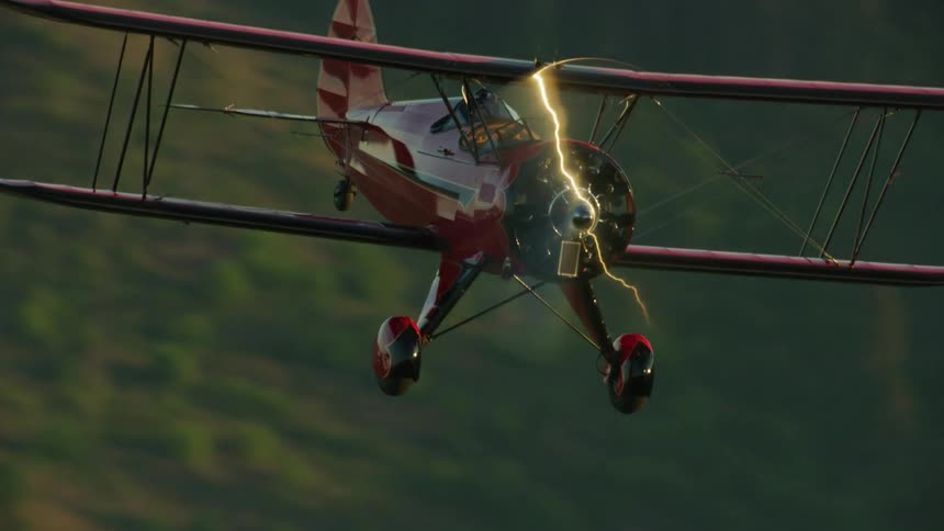 Sunlight creates a shining bolt of light on an airplanes radial engine and propeller as it flies