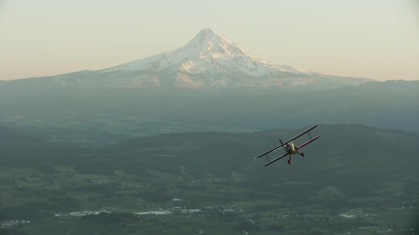 An airplane is flying around a mountainous area at dusk