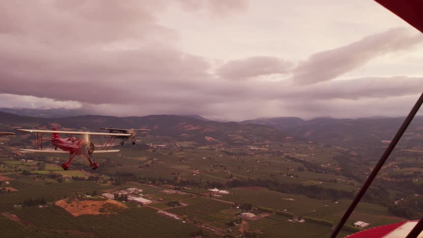 Three small planes fly together over countryside