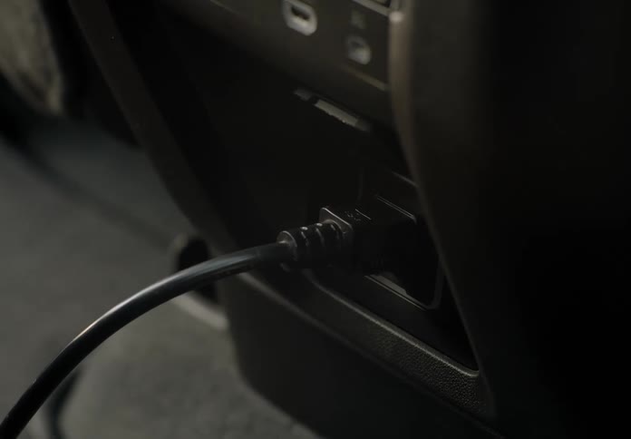 Close up of the hand of a man plugging a charger on the dashboard of a car