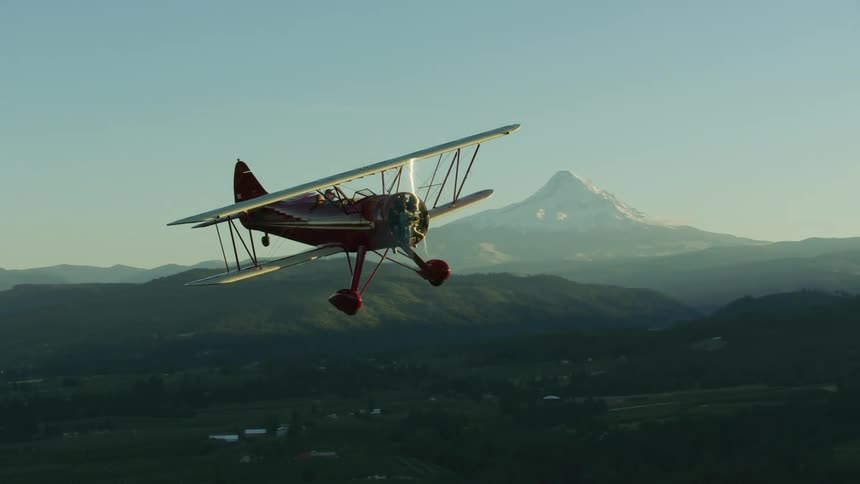 A small biplane WACO flying above Hood River and Mount Hood in Oregon