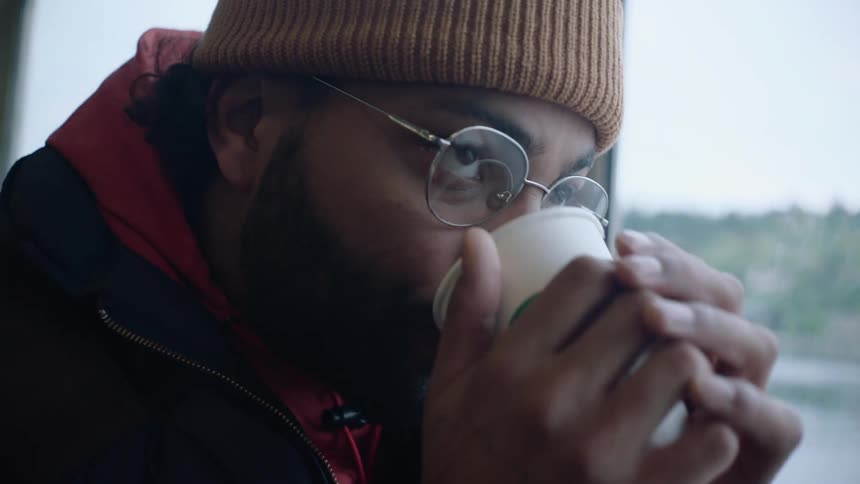 A man is sitting down and is drinking a cup of coffee
