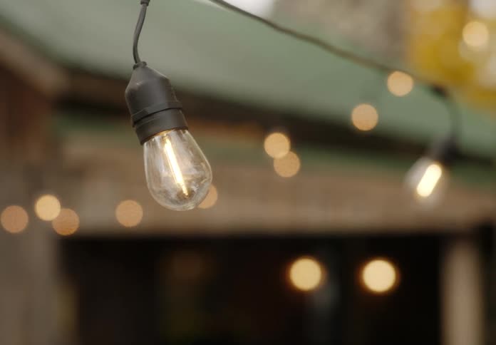 String of lights hanging near building sway in breeze and turn off