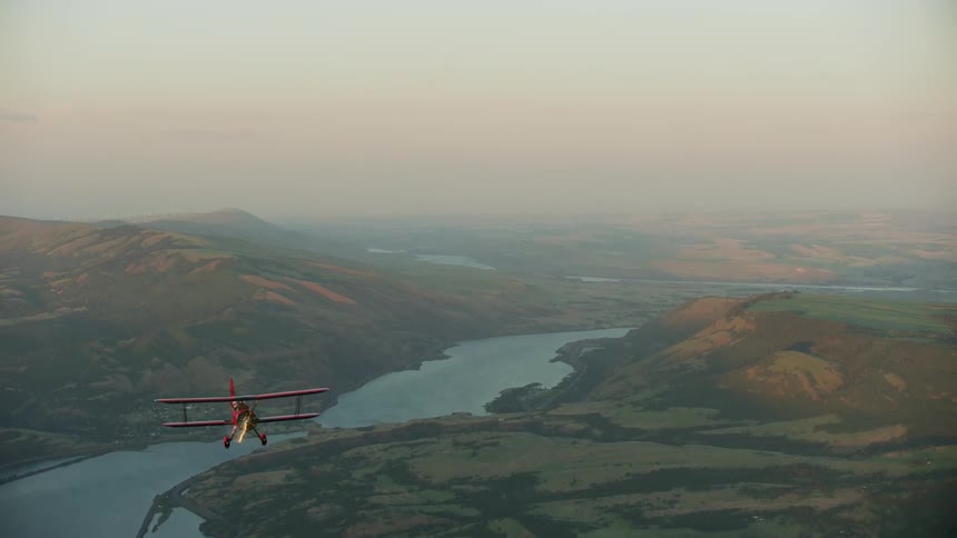 The red biplane glides high above the mountain and the Columbia River