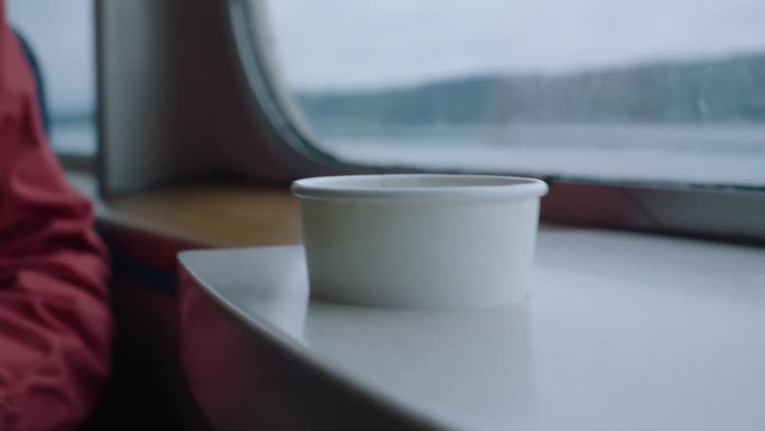 A person sits inside a boat next to a cardboard bowl