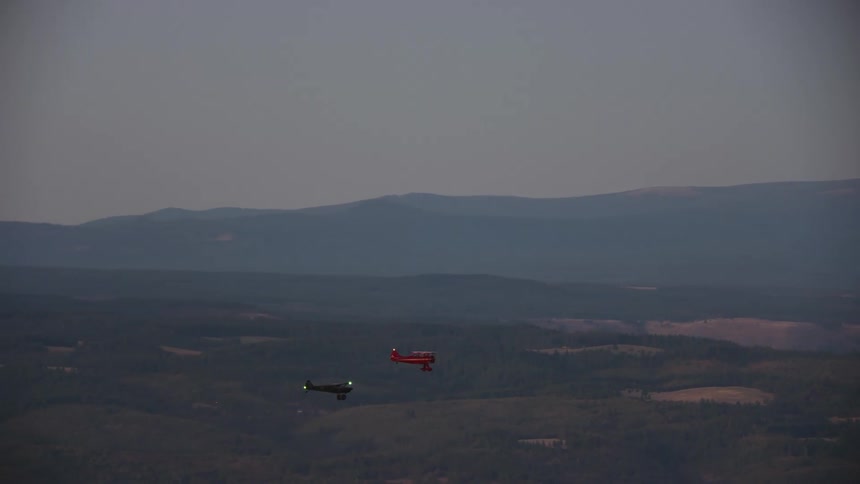 A WACO biplane and a Carbon Cub fly pas the desert in late evening