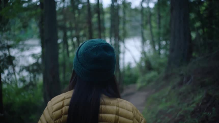 A woman is hiking outdoors in a wooded area
