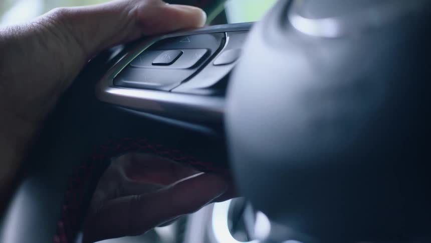 Person grasps steering wheel and turns in back and forth slightly to steer