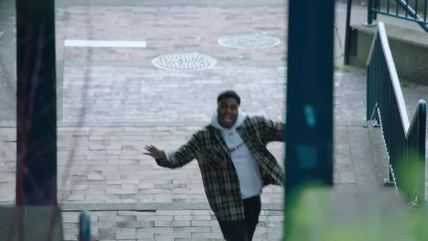A man is dancing outside of a building as he moves up the stairs