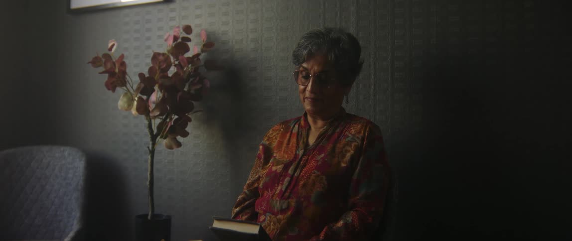A woman is sitting on a chair and reading a book