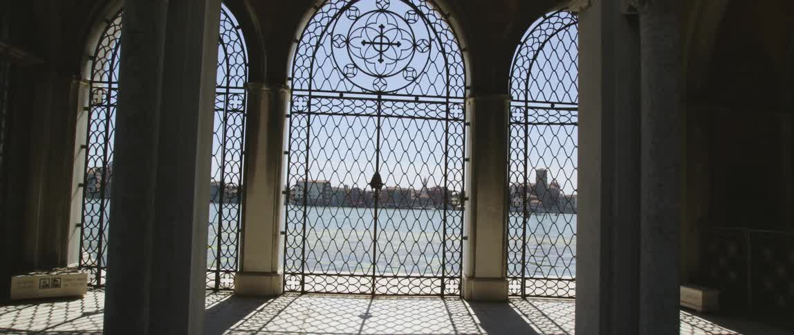 Gated floor to ceiling windows in a building offer views of downtown across the sea