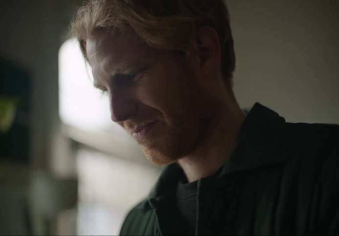 A man smiles to himself while sitting at home
