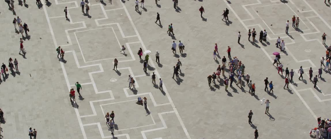 Pedestrians and tourists walk around an open outdoor plaza on a sunny day