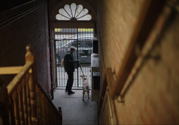 A man is leaving a building with his pet dog