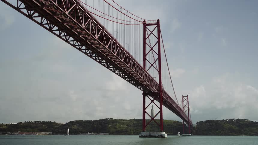 Sailboats sit under the Ponte 25 de Abril