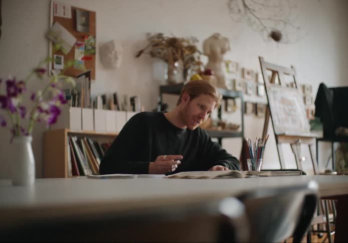 A man is sketching a picture and sitting at the table