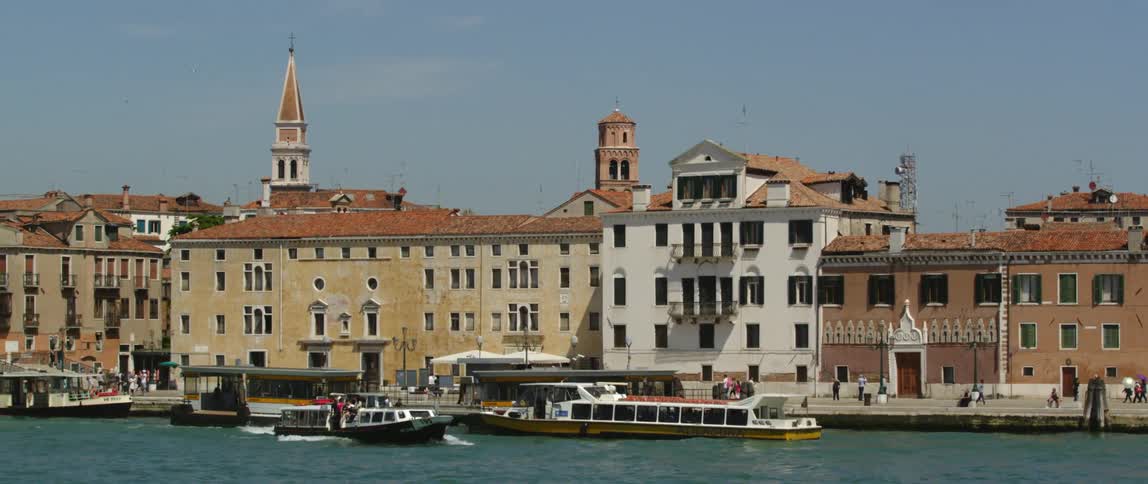 Boats and ferries sail past a historical city