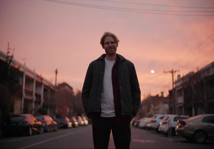 A man is standing in the middle of a road during sunset