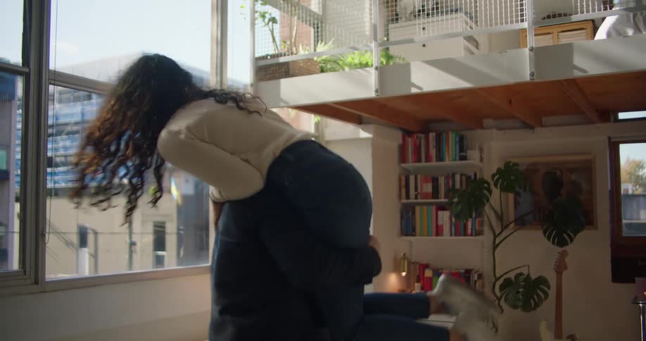 A man picks a woman up and they spin around then he puts her on the couch