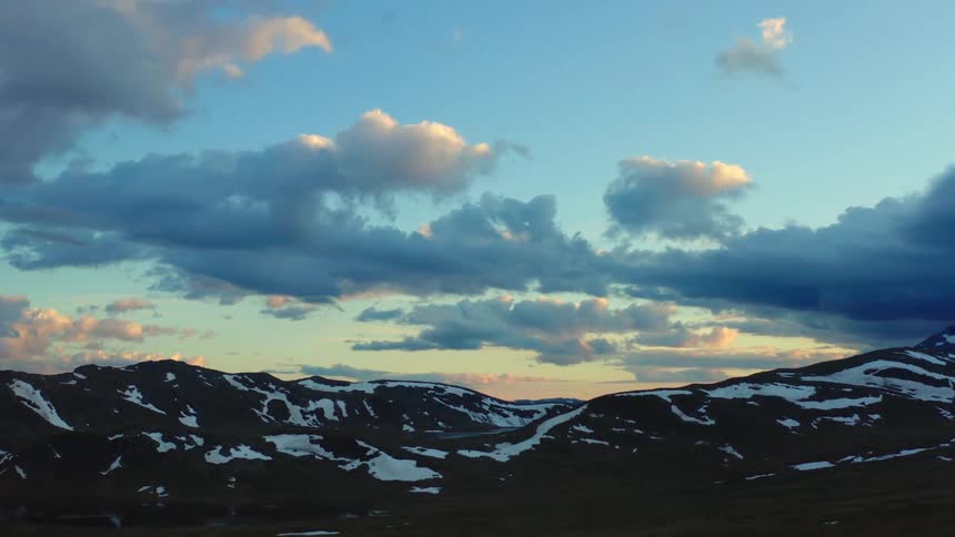 Mountain ridge with snow covering under a bright blue sky with cumulus clouds