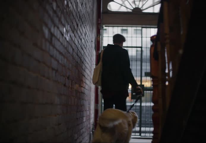 A man is walking his dog out of a building