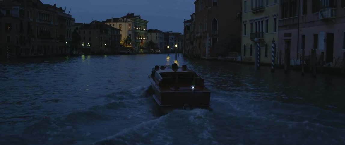 Boat travels along city canal at dusk in the city