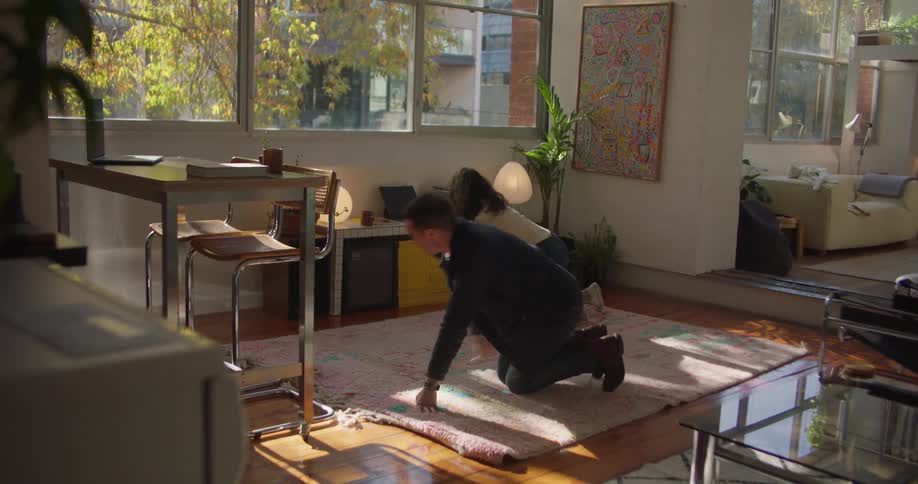 Two friends are moving furniture inside of there room