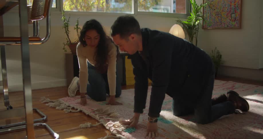 Two friends are putting a rug down on there floor