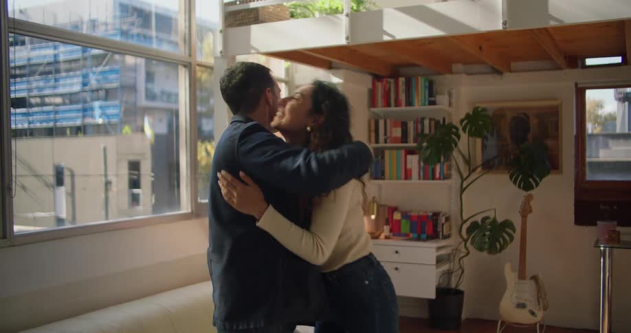 A couple are hugging and sitting down on the couch together