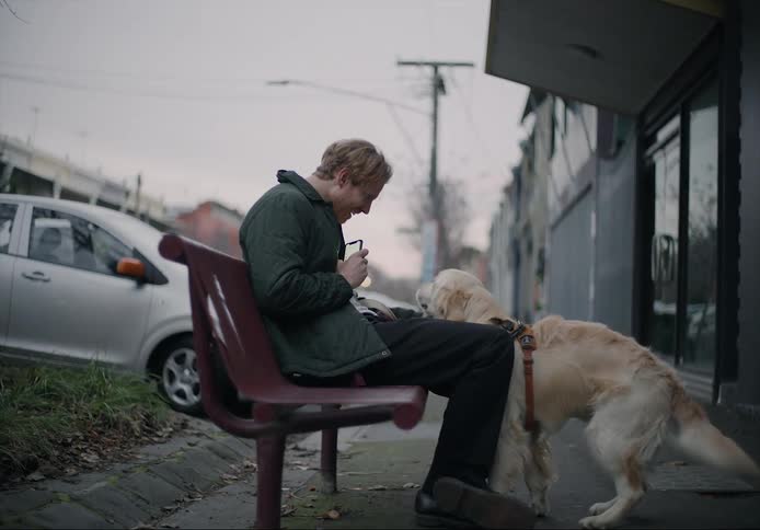 A man is sitting on a bench with his dog outdoors