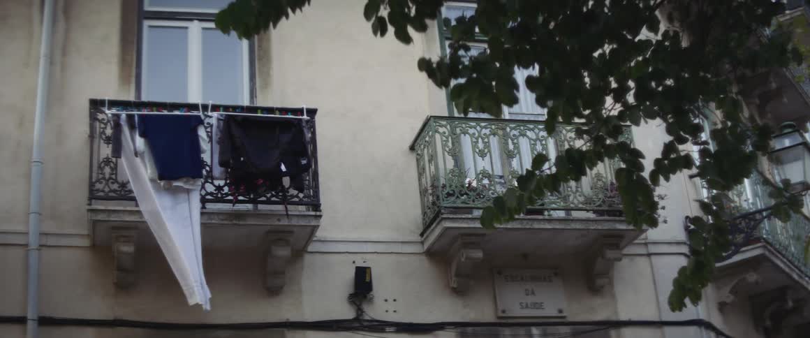 Clothes drying in the wind hanging from a balcony on the side of a building