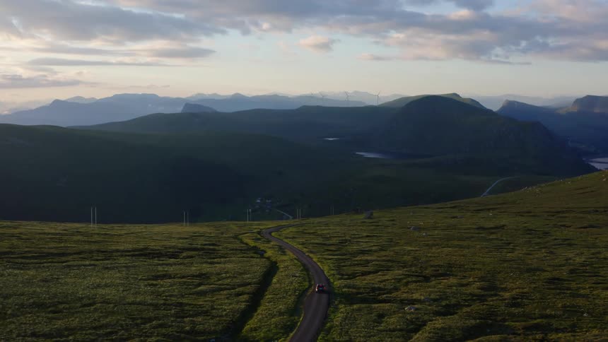 The view is of a car driving down the road in the forest area