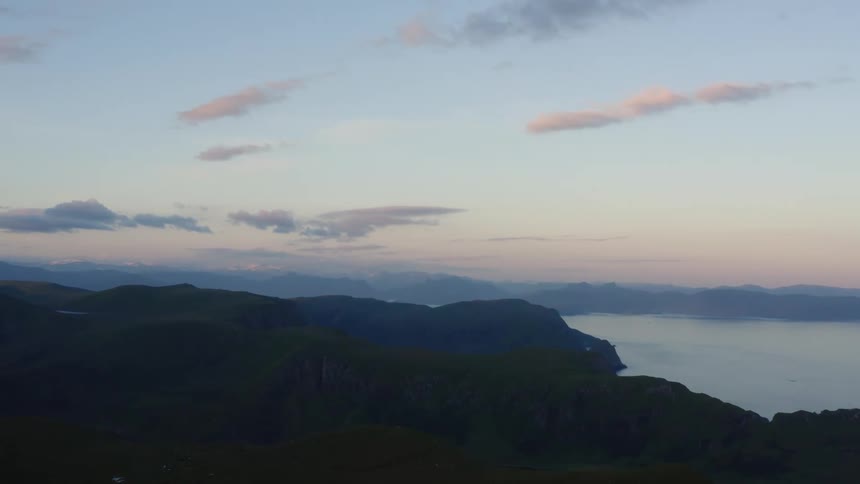 Mist covers mountains shore and lake under a red tinted sky
