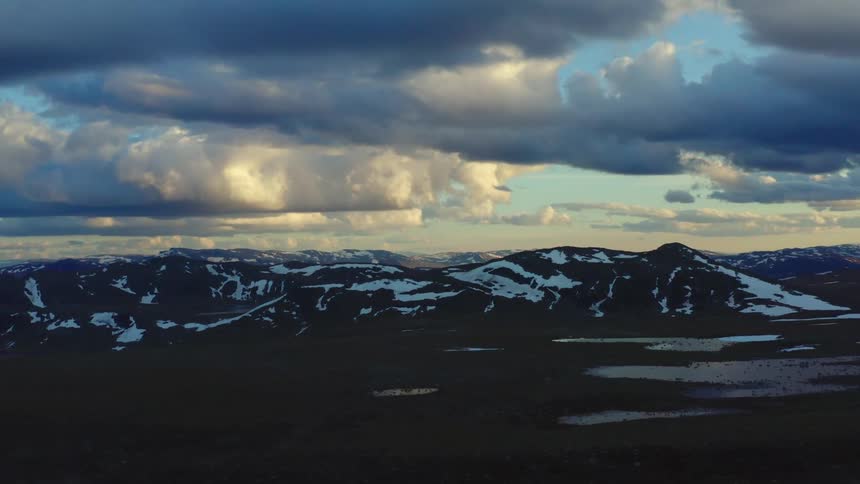 Aerial view of snow covered mountains at dusk is displayed