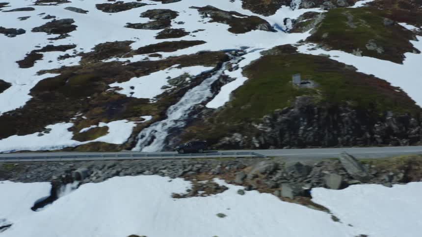 The view is of a car driving down the road in the nature area