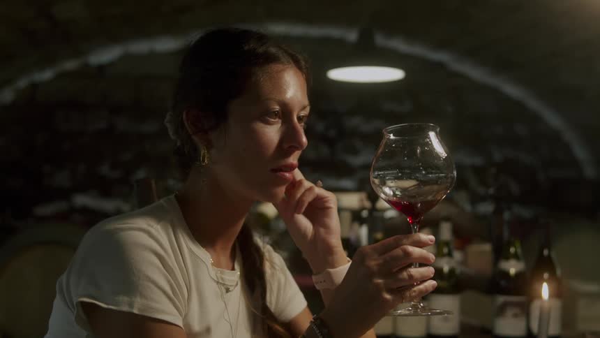 A woman is sitting at a table and drinking a glass of wine