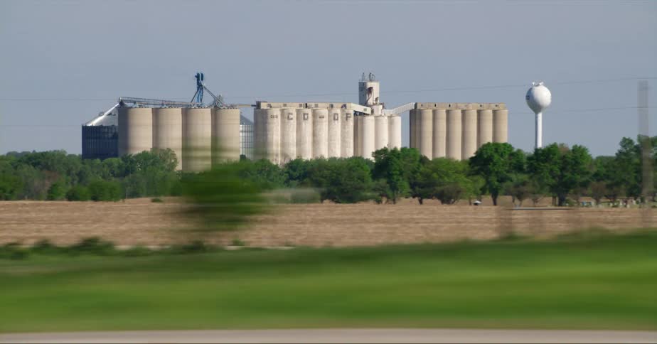 A grain elevator facility set back from the highway and passing traffic