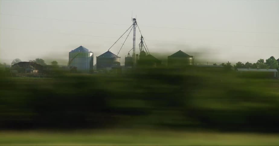 A large farm has giant silos and plowed fields