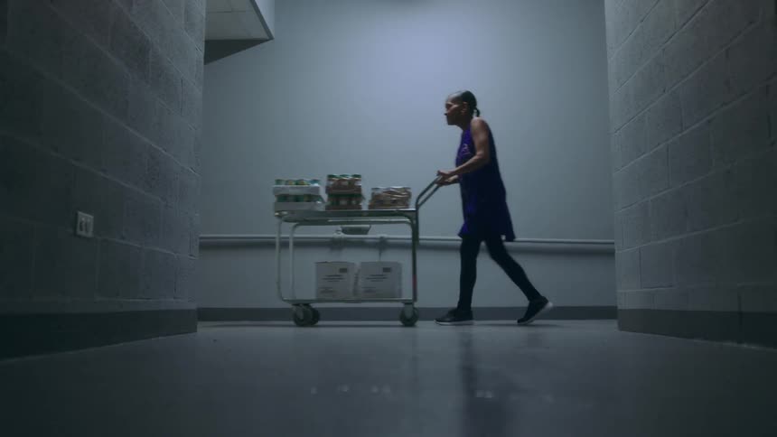 Woman pushes cart past intersecting hallway