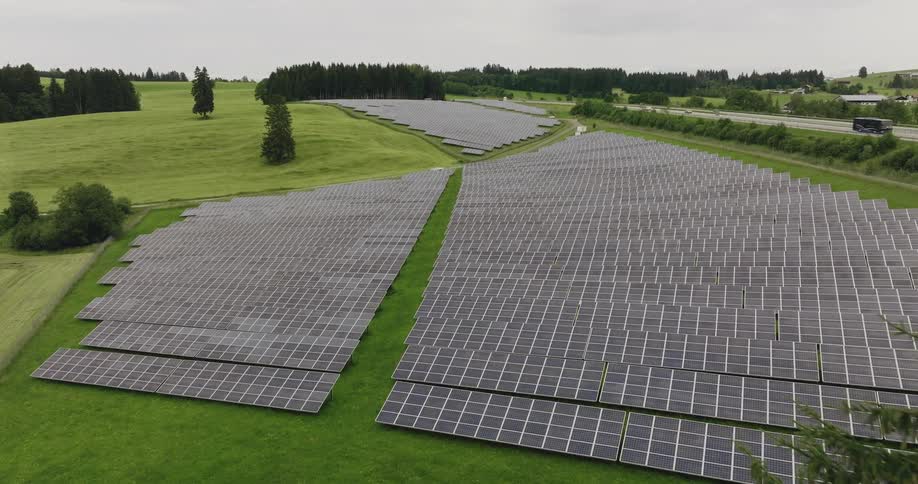 Solar panels lay in the field next to a highway