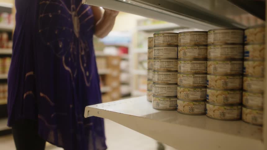 An employee is stocking food on shelves in a grocery store