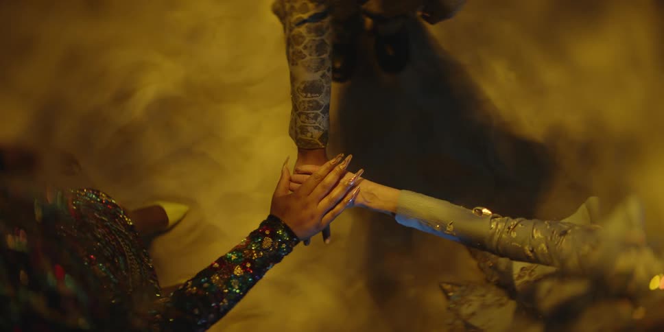 Woman wearing fine clothes reach their hands to the center to touch