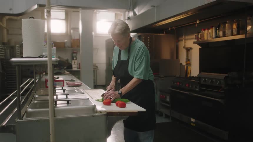 A man is cutting and preparing food in a kitchen