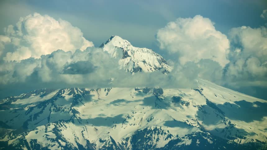 Mount Hood tight shot aerial with cumulous storm clouds building on the flank of the mountain in spring