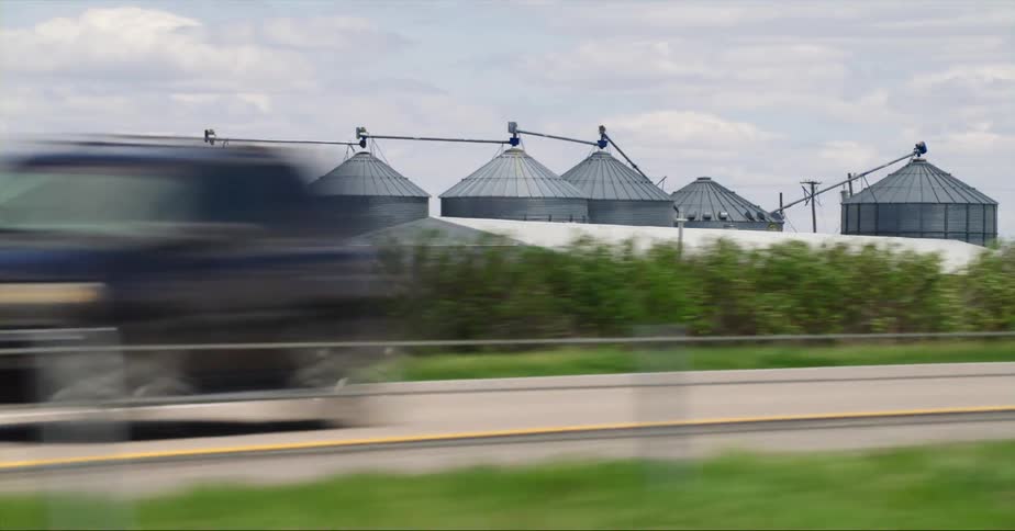 Cars are driving on a highway near farm land