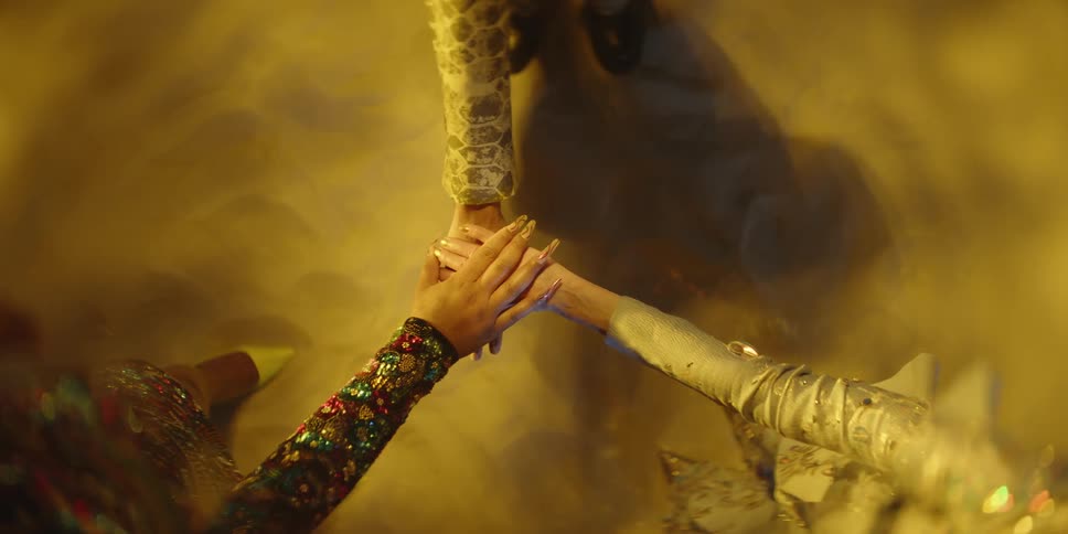 Three women reach into the center and place their hand one on top of the other
