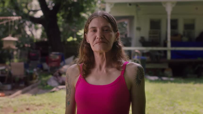 Woman stands in yard with home in the background