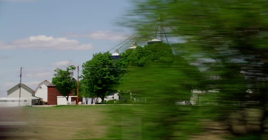 Blue grain silos of different height on a farm in the countryside seen from a moving vehicle